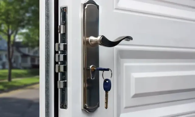 Detalle de varios tipos de cerraduras de seguridad en una puerta blanca, con una llave puesta.