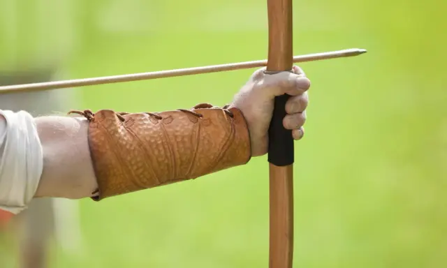 Mano con bracciale in cuoio, pronta a scoccare una freccia con l'arco, come un bellosguardo robin hood.