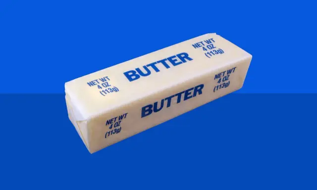 Ein Block Butter auf blauem Hintergrund. Bei Diabetes ist die Frage, wie viel Butter erlaubt ist.