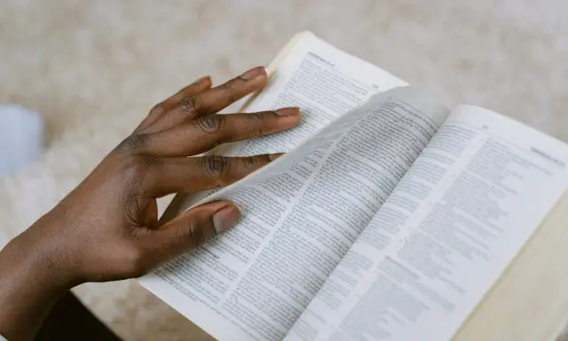 Dłoń przewracająca strony Biblii, szukająca pocieszenia w Psalmie 27.