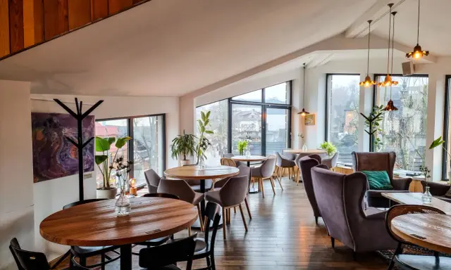 Przytulna restauracja w Bukowinie Tatrzańskiej z widokiem na góry. Drewniane stoły, wygodne fotele i stylowe oświetlenie tworzą ciepłą atmosferę.