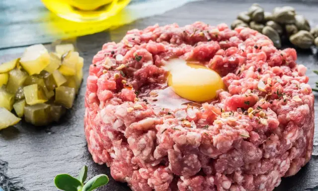Un delicioso steak tartar con huevo crudo, alcaparras, pepinillos y aceite de oliva.