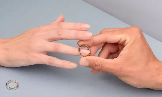 Manos unidas, un anillo dorado listo para ser colocado en el dedo anular, el lugar donde se pone el anillo de compromiso.