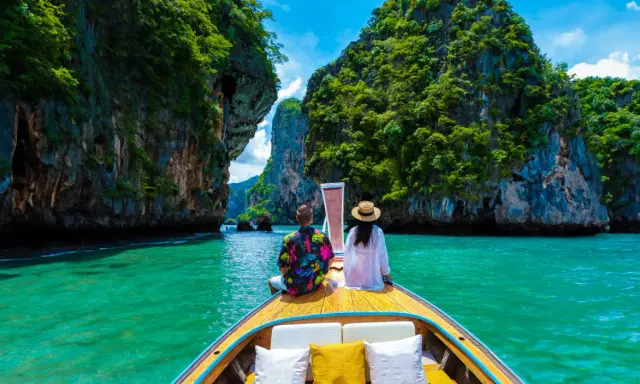 Para w łodzi podziwia turkusową wodę i skaliste wyspy. Idealna pogoda na Phuket w grudniu.