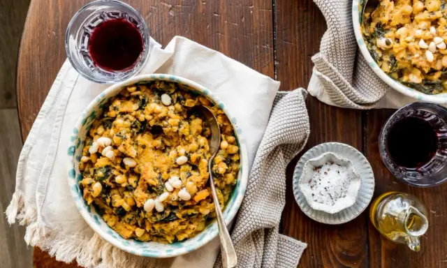 Un piatto rustico di fagioli e verdure, perfetto per scoprire cosa mangiare in Toscana. Accompagnato da vino rosso e olio d'oliva.