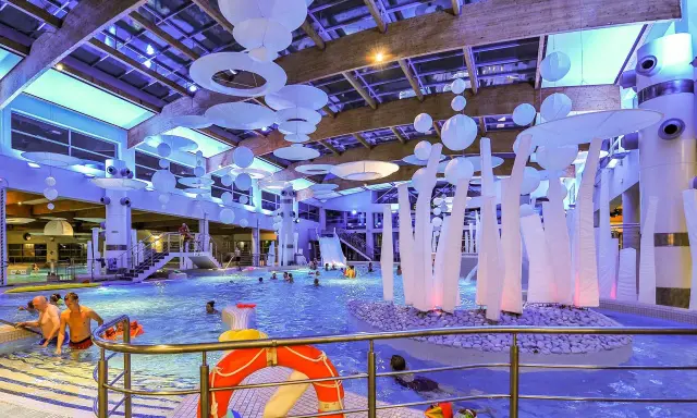 Wesoła zabawa w aquaparku w Sopocie, mnóstwo ludzi cieszy się basenem i atrakcjami. Warto sprawdzić aquapark Sopot opinie przed wizytą.
