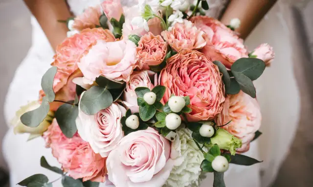 En vacker bukett med rosa rosor, nejlikor och eukalyptus. Perfekta blommor till dukning för ett romantiskt bröllop.