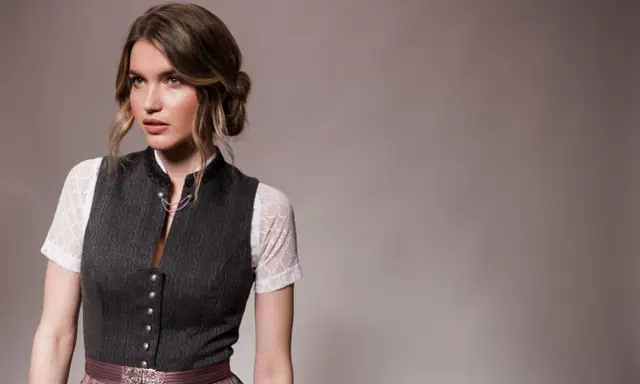 Eine Frau mit einer eleganten Dirndl-Frisur für kurze Haare trägt ein traditionelles Dirndl.