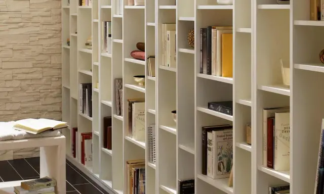 Eine weiße, modulare Bücherwand, perfekt für dein Projekt "Bibliothek selber bauen". Viele Bücher und Deko-Objekte sind ordentlich einsortiert.