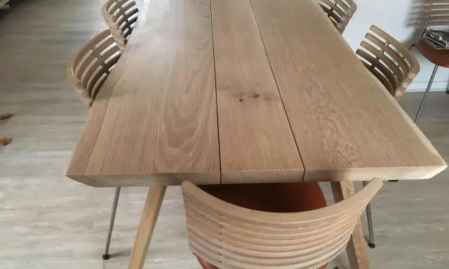 Oljat ekbord med ljusare träyta och moderna stolar med träribbor.