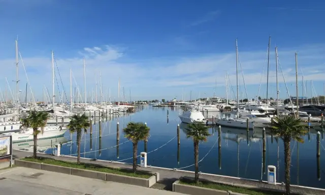 Porto turistico di San Giuliano Mare, Rimini, con barche a vela e yacht ormeggiati in un mare calmo sotto un cielo azzurro.