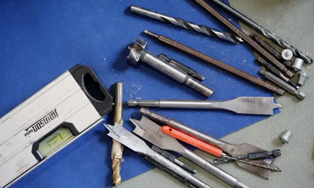 Niveau à bulle et divers outils du maçon, incluant des forets et des mèches, prêts pour le travail.