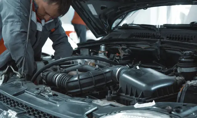 Mechanik pracuje przy silniku VW. Dowiedz się, ile kosztuje wymiana oleju w serwisie VW.