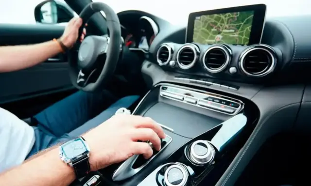 Mano en la palanca de cambios de un coche deportivo moderno, demostrando que los coches eléctricos tienen marchas.