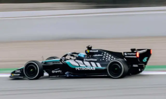 El Aston Martin AMR26 negro y turquesa acelera en la pista, con el logo de Petronas visible.