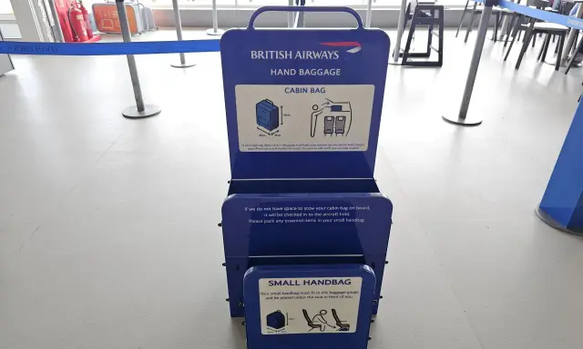 Niebieska miarka bagażu podręcznego British Airways na lotnisku. Sprawdź wymiary swojego bagażu kabinowego.