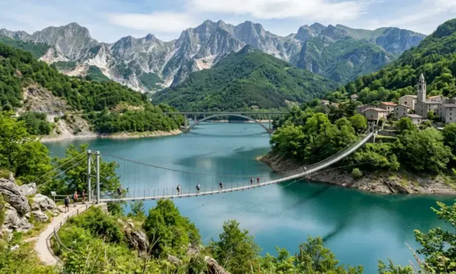 Un ponte sospeso attraversa il lago di Vagli, con montagne imponenti e un borgo pittoresco sullo sfondo.