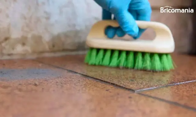 Guante azul cepilla suelo de baldosas para quitar cemento cola.