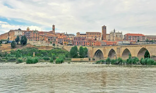 Un pintoresco pueblo con un puente de piedra sobre un río, ideal para visitar si buscas pueblos bonitos cerca de Valladolid.