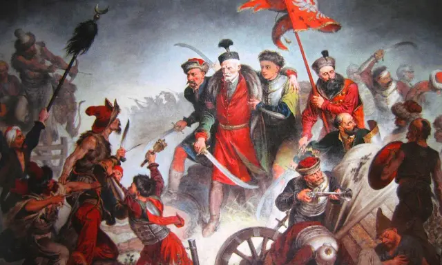 Obraz przedstawia zaciętą bitwę pod Kłuszynem 1610. Polscy żołnierze walczą z wrogiem, wznosząc sztandar z orłem.