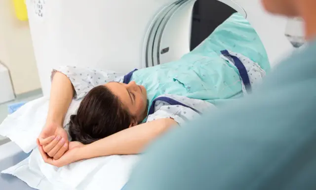 Pacjentka leży w skanerze tomografii komputerowej, badanie może pomóc zdiagnozować metaplazję pęcherza moczowego objawy.
