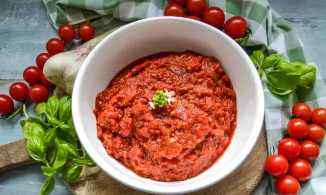 Frische tomaten pizza sauce, mit Basilikum und Knoblauch, umgeben von reifen Kirschtomaten.