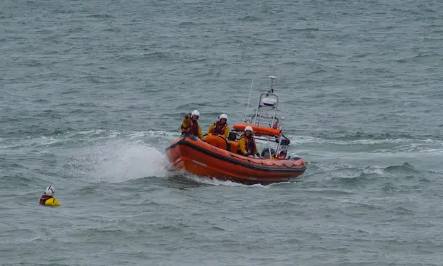 Bateau de sauvetage orange avec équipage en action. Une personne dans l'eau, une fusée de détresse bateau obligatoire est essentielle.