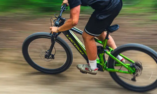 Mężczyzna na zielonym rowerze elektrycznym Lectron pędzi po leśnej ścieżce. To inspiracja, jak wybrać rower elektryczny dla siebie.