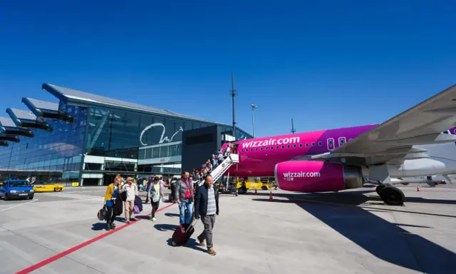 Pasażerowie wsiadają do różowego samolotu Wizz Air na jednym z portów lotniczych w Polsce.