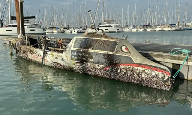 Un bateau coulé, couvert de coquillages, est amarré dans un port. Le nom "Talisker Whisky Atlantic Challenge" est visible.