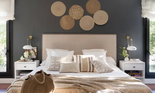 Decorar pared cabecero con fotos de mimbre crea un ambiente acogedor. Cama con cojines y manta tejida.