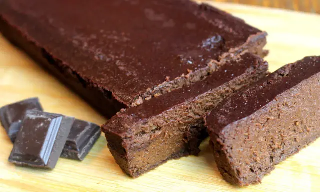 Un délicieux gâteau chocolat compote, coupé en tranches, avec des carrés de chocolat à côté.