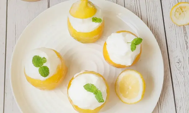Quatre citrons givrés garnis de crème et de menthe, prêts à être dégustés. Un délice rafraîchissant !