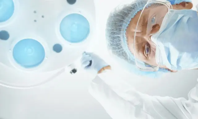 Chirurg w masce i okularach pochyla się nad pacjentem, przygotowując zalecenia po operacji prostaty.