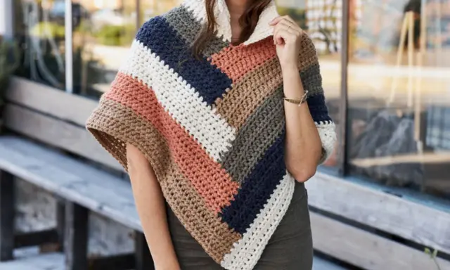 Mujer con un poncho de ganchillo a rayas en tonos tierra, azul marino y blanco. El patrón poncho es ideal para el otoño.