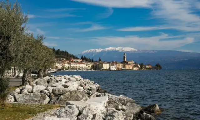 Vista di un borgo sul lago, con montagne innevate sullo sfondo. Perfetto per sapere dove andare 2 giorni in vacanza nord Italia.
