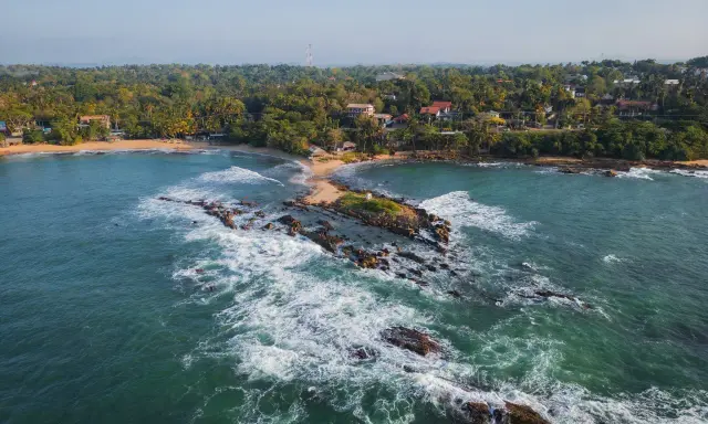 Malownicze wybrzeże, gdzie leży Sri Lanka. Tropikalna roślinność, plaże i skaliste wysepki w turkusowej wodzie.