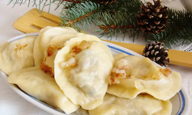 Pyszne pierogi z mięsem i kapustą, ozdobione gałązkami świerku i szyszkami, wyglądają jak świąteczny przysmak.