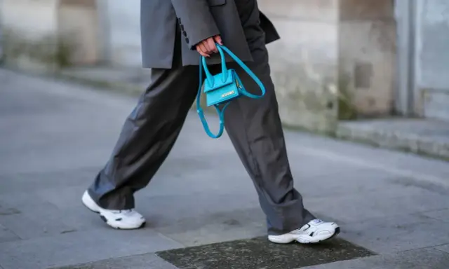 Elegancki damski garnitur w połączeniu z białymi sneakersami i turkusową torebką.