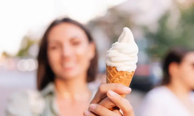 Kobieta trzyma lody na ból gardła. Słodka ochłoda w upalny dzień.