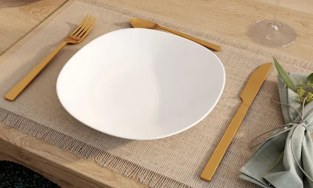 Une assiette blanche est dressée sur un set de table, avec la position des couverts à la française : fourchette à gauche, couteau à droite.