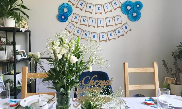 Urocze dekoracje na chrzest diy: girlanda "Chrzest Święty", bukiety białych kwiatów i ozdobne napisy.