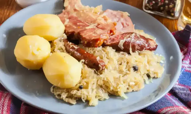 Une assiette de choucroute garnie, avec pommes de terre, saucisses et viande fumée. Un plat qui raconte une histoire culinaire.