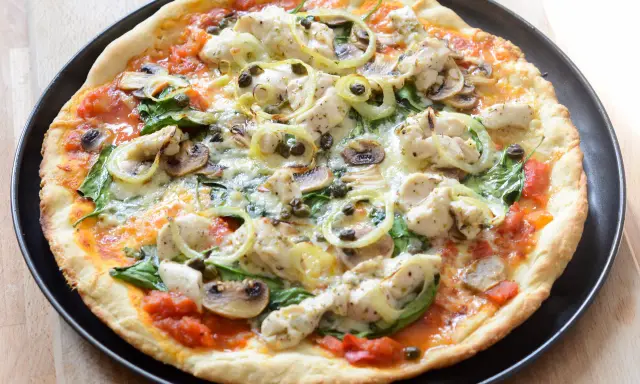 Pyszna pizza z kurczakiem, pieczarkami, szpinakiem i kaparami na cienkim cieście.