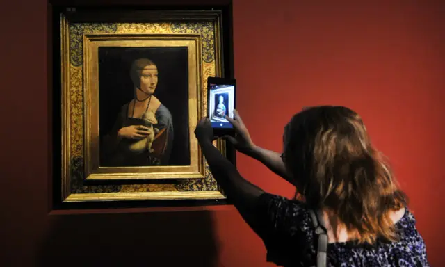 Dama z łasiczką w muzeum, gdzie jest? Kobieta robi zdjęcie słynnego obrazu telefonem.
