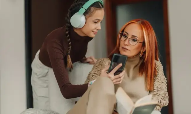 Matka z córką omawiają zasady w domu dla nastolatków, patrząc na telefon.