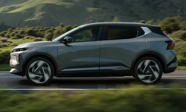 Nowy, elektryczny Mitsubishi Eclipse Cross sunie po malowniczej drodze, otoczony zielonymi wzgórzami.