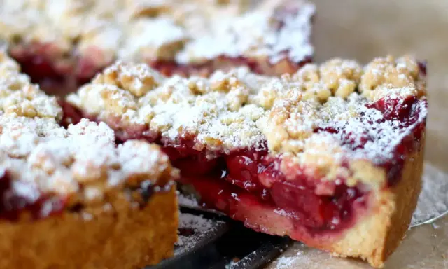 Ein saftiger Kirschstreuselkuchen, bestäubt mit Puderzucker, wartet darauf, genossen zu werden.