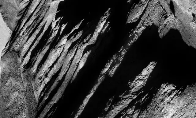 Abstract black and white landscape, reminiscent of Aaron Siskind photos, with dramatic shadows and textured rock formations.