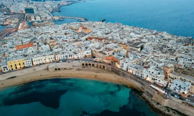 Vista aerea del centro storico di Gallipoli, con case bianche, mare turchese e un arco sul lungomare. Scopri cosa vedere a Gallipoli centro storico.
